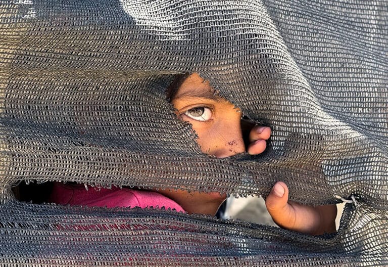 Una niña se asoma tras una tienda improvisada en el puerto en la Ciudad de Gaza