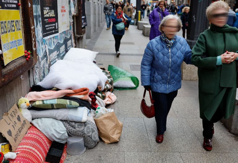 Dos mujeres pasan ante los enseres de un 'homeless' en Madrid.