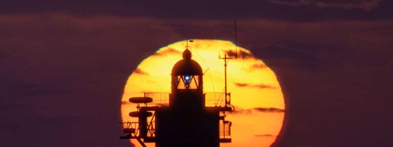 El sol sale junto al faro de Punta Gavioto en Puerto del Rosario (Fuerteventura)