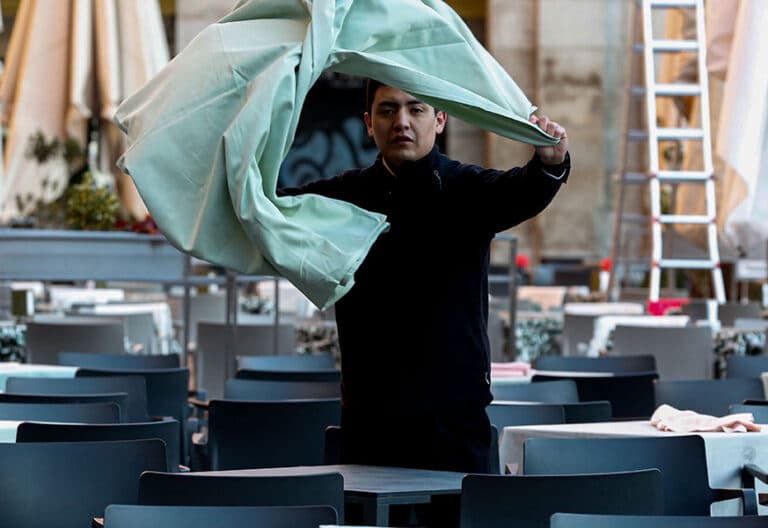 Un camarero migrante prepara las mesas de una terraza en el centro de Madrid