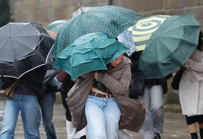Varias personas se protegen de la lluvia y el viento en Santiago de Compostela