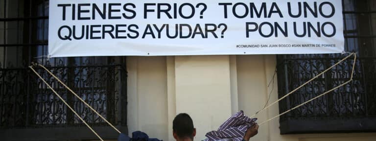 Una persona "sin techo" que toma ropa colocada a un costado de la Catedral Metropolitana de ciudad de Guatemala (Guatemala), para ayudar a los más vulnerables durante la época más fría en el país.