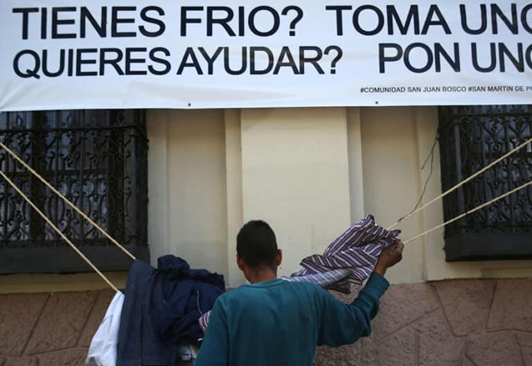 Una persona "sin techo" que toma ropa colocada a un costado de la Catedral Metropolitana de ciudad de Guatemala (Guatemala), para ayudar a los más vulnerables durante la época más fría en el país.