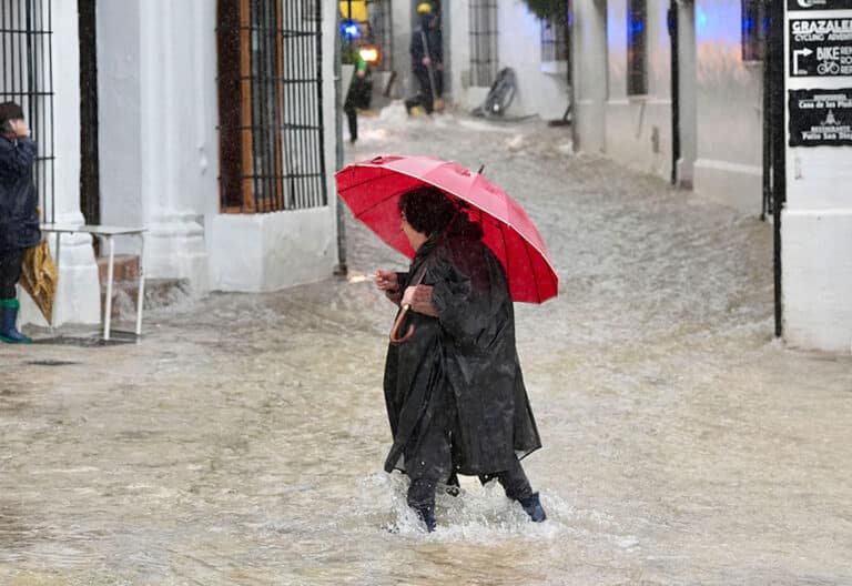 Una vecina de Grazalema (Cádiz) camina por una calle inundada debido a las intensas lluvias