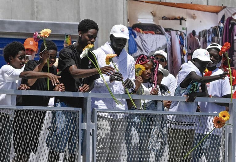 Migrantes lanzando flores al mar. Arguineguín