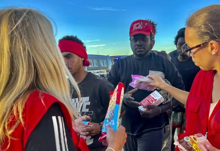 Voluntarias de Cruz Roja reparten alimentos a los migrantes de Ceuta. Foto: Efe