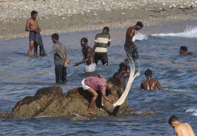 Migrantes lavan su ropa en una playa de Ceuta. Foto: Efe