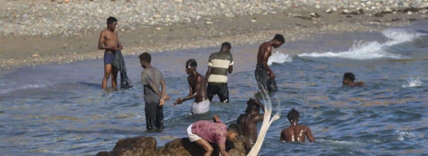 Migrantes lavan su ropa en una playa de Ceuta. Foto: Efe